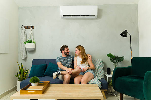 istock Happy couple relaxing on sofa under air conditioning unit at home 2209077107