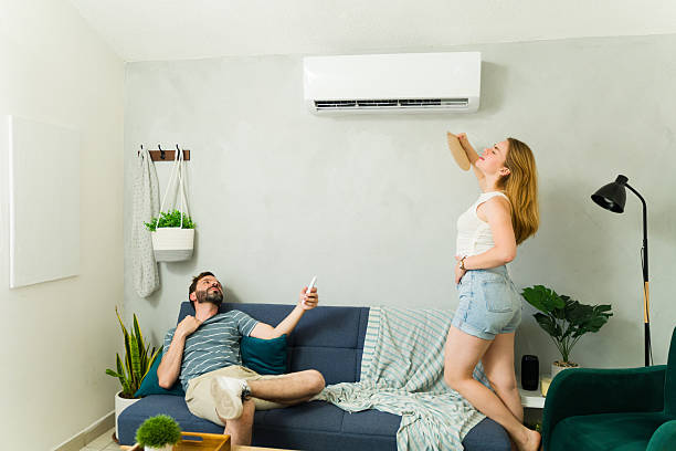 istock Couple cooling down at home using air conditioning unit on hot summer day 2209077197