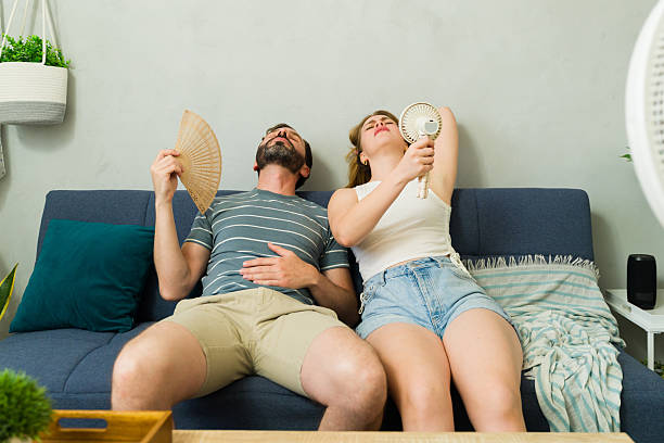 istock Overheated couple sweating at home during summer heat wave 2209077285