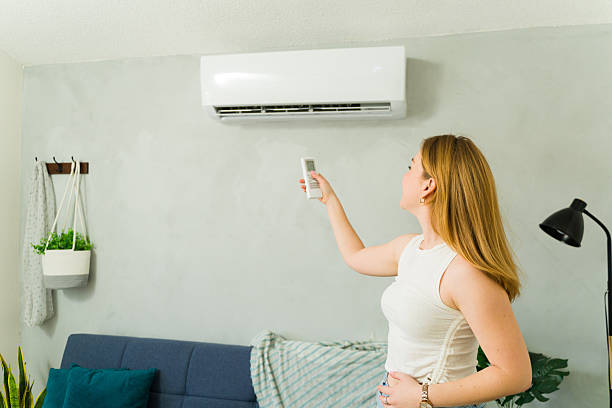 istock Woman adjusting air conditioning temperature using remote control at home 2209077342