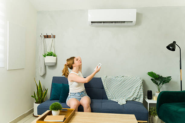 istock Woman feeling hot using remote control to turn on air conditioner 2209077384