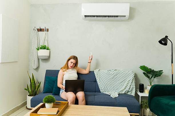 istock Attractive woman working from home using laptop and turning on air conditioning 2209077399