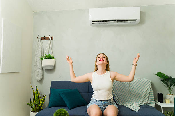istock Woman feeling refreshed at home with air conditioning unit 2209077438