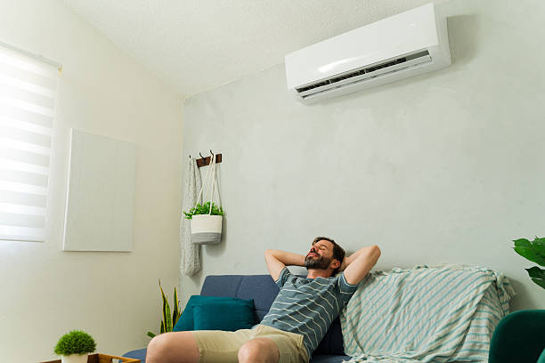 istock Man relaxing on sofa under air conditioning unit at home 2209077472