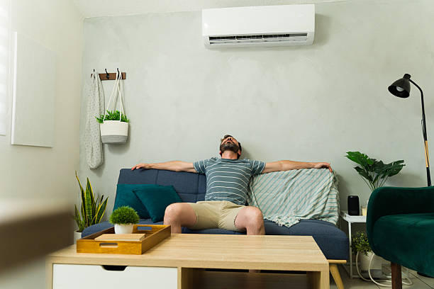 istock Man relaxing on sofa under air conditioning unit at home 2209077488