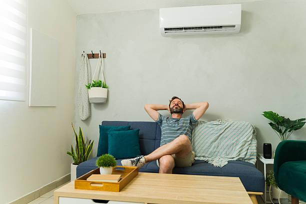 istock Happy Caucasian man relaxing on sofa under air conditioning unit at home 2209077537