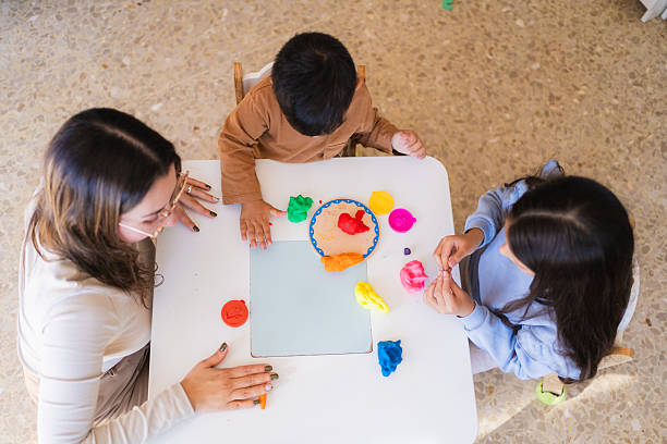 istock Teacher and children playing with modeling clay in kindergarten 2209078899