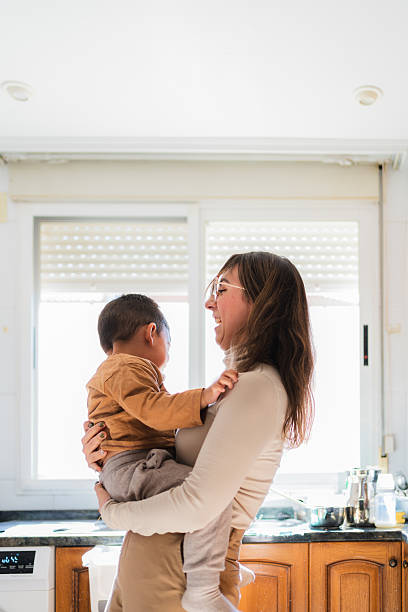 istock Mother holding and playing with her baby son in a kitchen 2209078920