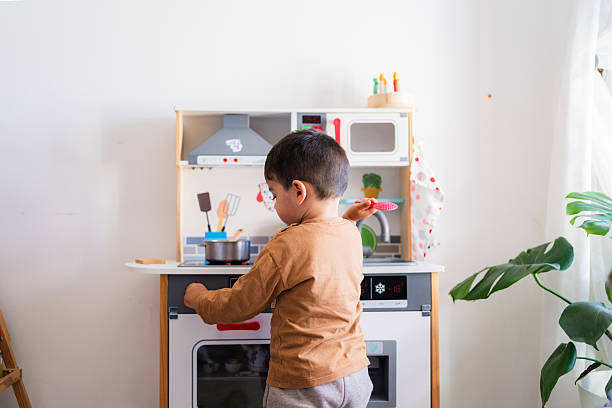 Young boy having fun playing with toy kitchen set, showing imagination and creativity in domestic role-playing