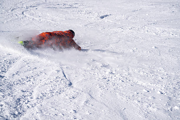 Snowboarder descends mountain at ski resort on a blue sky day, takes sharp turn, Swiss Alps
