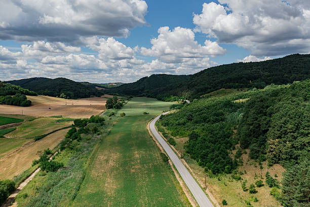istock Winding road through green valley with forests and farmland 2209082771