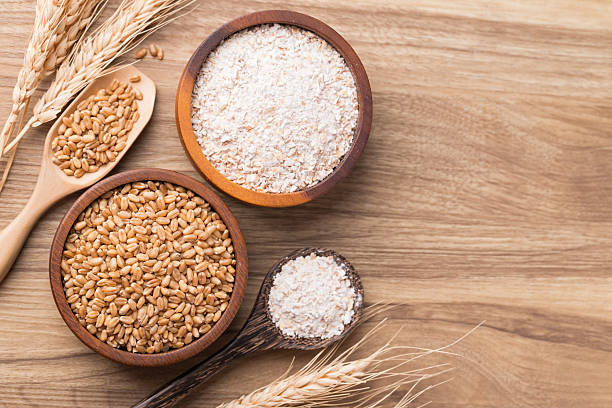 istock Whole wheat flour with wheat grain in bowl on wooden background, Table top view 2209085421