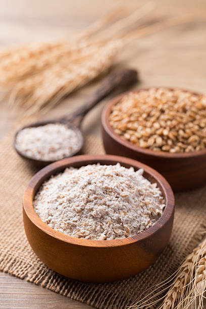 istock Whole wheat flour with wheat grain in bowl on wooden background 2209085437