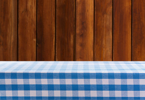 Empty blue and white checkered tablecloth on old wooden background