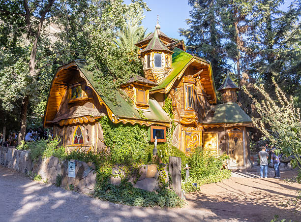 Green and red fairy house with a yellow fairy door on the forest floor in a woodland fairy garden in Ireland.
