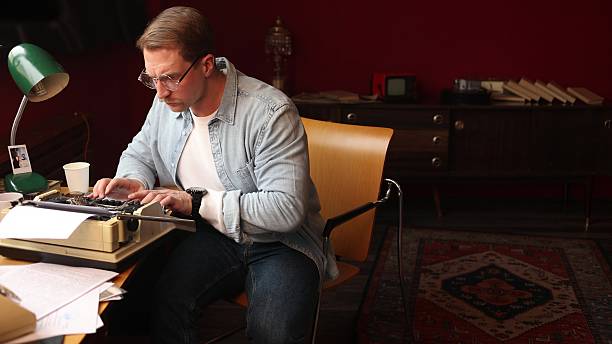 istock Young male novelist deep in thought at classic typewriter, 2209111896