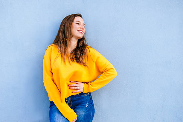 istock Woman leaning against blue wall, smiling and looking away 2209116470