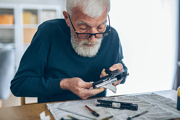 istock Senior man cleaning his weapon at home 2209119072