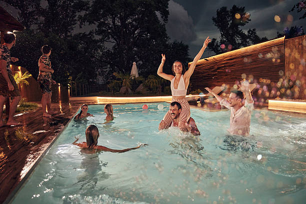 istock Cheerful friends having fun in the pool at night. 2209119348