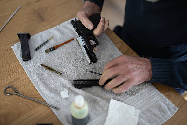 Detailed close-up shot of disassembly and the cleaning process of a gun firearm. Trained professional technician removing parts to clean and perform maintenance