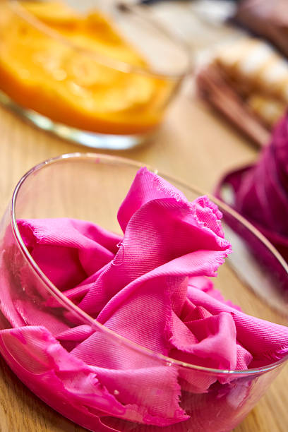 side view of glass flasks with dyed bright fuchsia-colored fabrics, closeup
