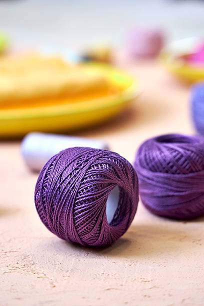 A stack of bright, multicolored yarn balls is prominently displayed, showcasing different hues and textures, ideal for knitting and crafting enthusiasts.