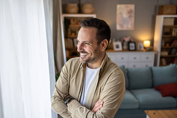 istock Happy man smiling and looking out the window at home 2209124383