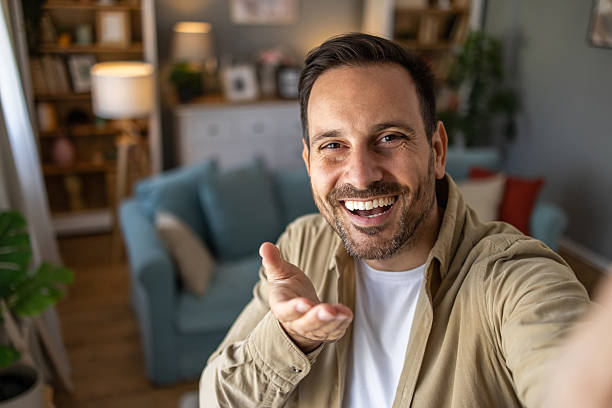 istock Happy man taking a selfie at home, smiling and gesturing 2209124398
