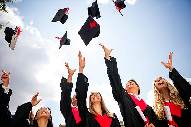 istock Joyful graduates celebrate academic success outdoors by throwing caps into the sky under a bright summer day. 2209126240