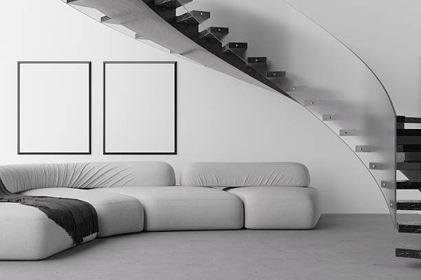 Modern living area features a sleek sofa in grey tones complemented by blank frames on the wall. This open space invites personalization and creativity with its minimalist design. 3D render.
