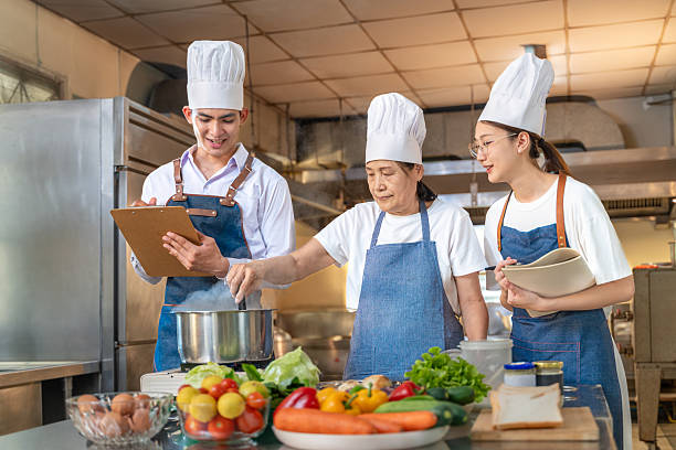 istock Senior female chef instructor showing her students how to cook while they are taking notes 2209134827
