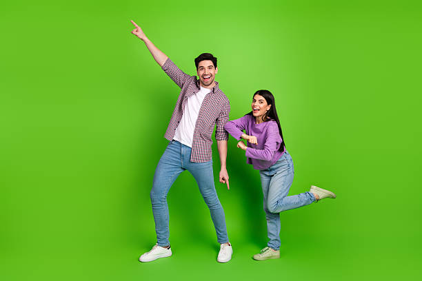 istock Young couple playfully posing together against vibrant green background, expressing joy and fun in casual modern fashion and style 2209139021