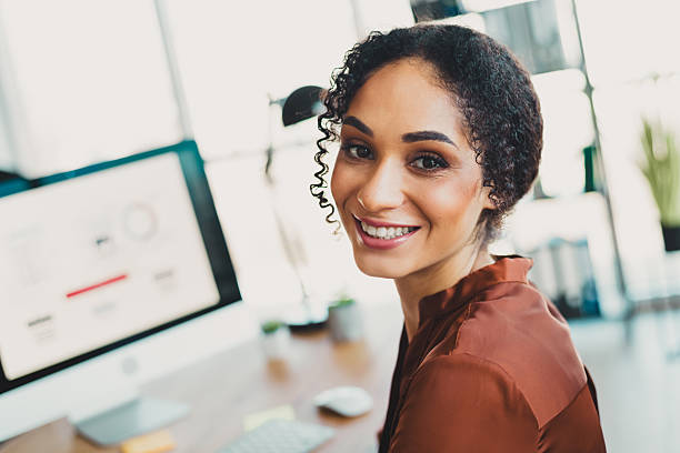 istock Young black businesswoman with a bright smile working in a modern office environment surrounded by natural daylight and professional decor 2209140432