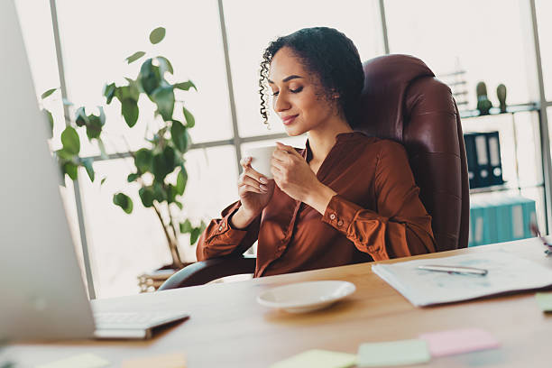 istock Young businesswoman enjoying a coffee break while working in a modern office with natural daylight and professional atmosphere 2209140534