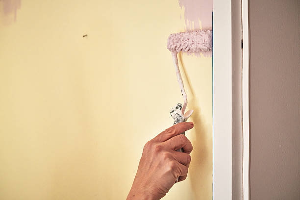 istock Painting a Wall Along Painter`s Tape by Using Paint Roller to Cover the Surface 2209142173