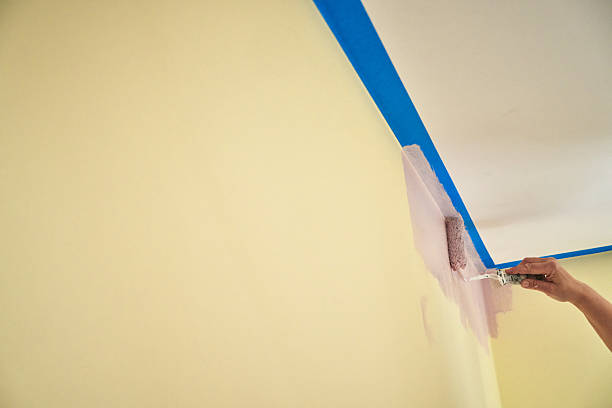istock Painting a Wall Along Painter`s Tape by Using Paint Roller to Cover the Surface 2209142465
