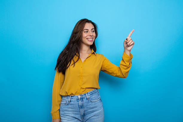 istock Woman pointing finger indicating direction against blue background 2209143098