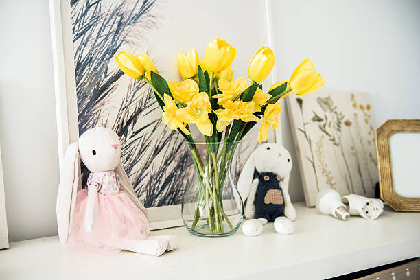 istock Plush bunnies next to a vase with yellow flower on a shelf decor for Easter 2209143267
