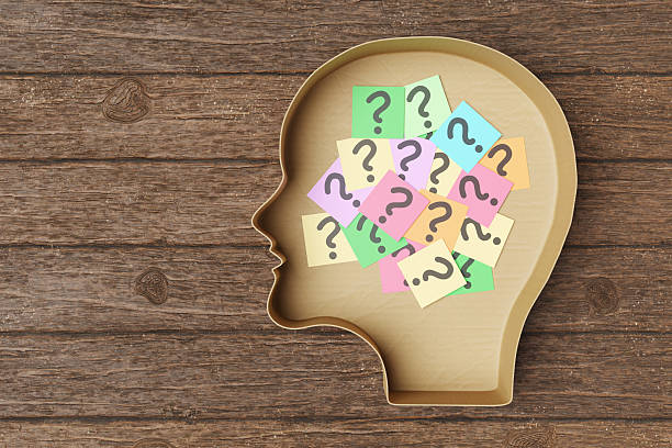 istock Colorful sticky notes written with a question mark in a human head shaped cardboard on a wooden table. Illustration of the concept of thoughts, confusion and uncertainty 2209143669