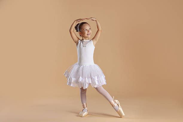 istock Little ballerina practicing dance moves on beige background 2209147986