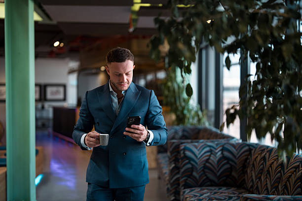 istock Professional Businessman Checking Mobile Phone While Having Coffee In Modern Office Lounge 2209151698
