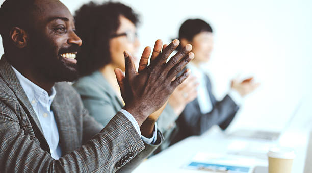 Smiling male adult clapping hands and cheering on job well done, enjoying a significant win. Excited black man expressing his congratulations with an applause gesture and positive response.