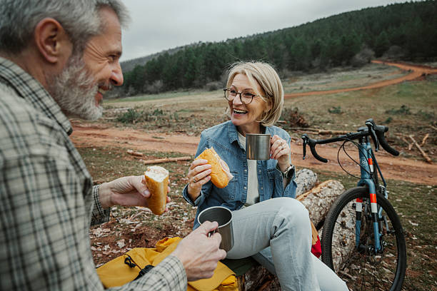istock Mature cycling couple having breakfast and coffee on a tree log 2209156592