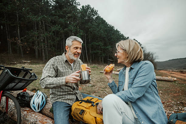 istock Mature cycling couple having breakfast and coffee on a tree log 2209156599