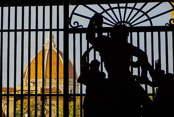 Duomo Santa Maria del Fiore (Florence Cathedral) shines brightly behind a statue in the Uffizi Gallery, Florence.