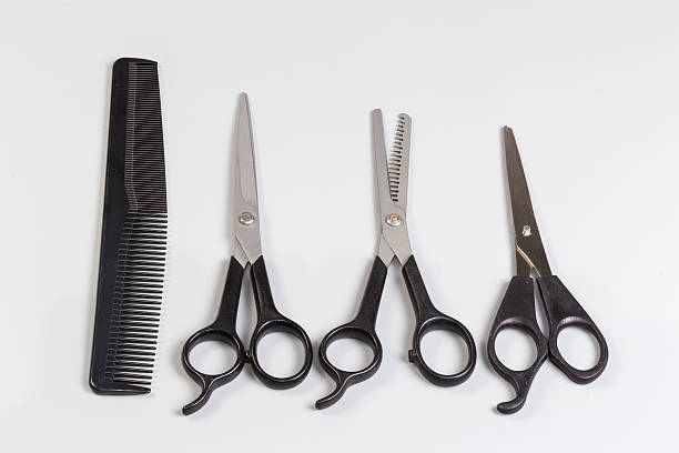 Several pairs of the professional stainless steel normal hairdressers scissors and hair thinning scissor, one plastic comb on a gray background