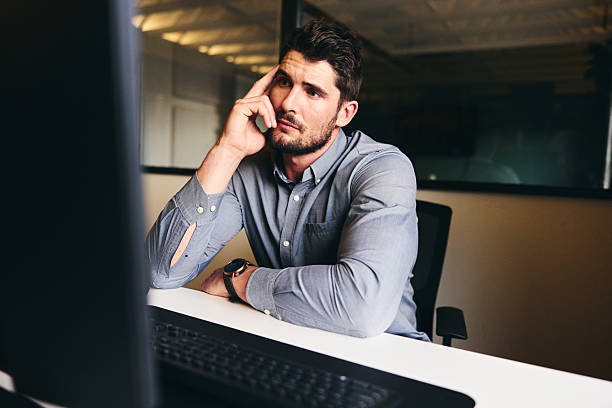 istock Mid adult businessman at desk with anxious expression, looking at computer 2209164571