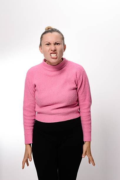 Young woman growling like an animal, making cat claws gesture. White background.