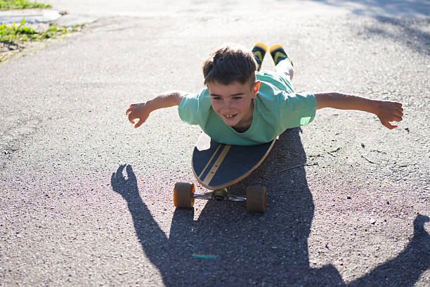 istock Cheerful boy lying on skateboard with open arms 2209165722