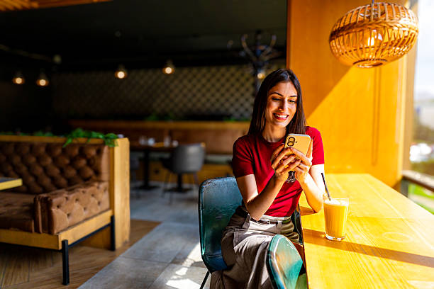istock Young woman using smartphone and drinking latte in a cafe 2209165884